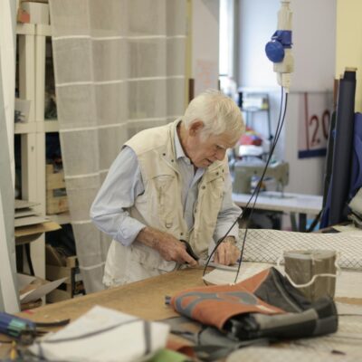 Elderly tailor concentrating on fabric cutting in his workshop, showcasing traditional craftsmanship.