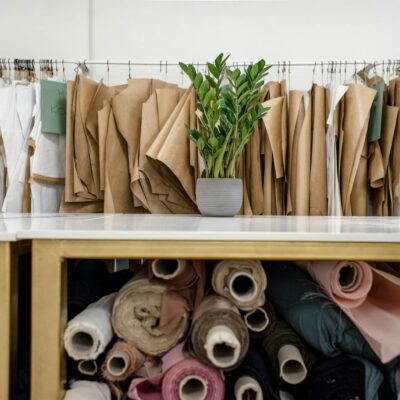 Interior of a fashion studio featuring fabric rolls and dress patterns on hangers.